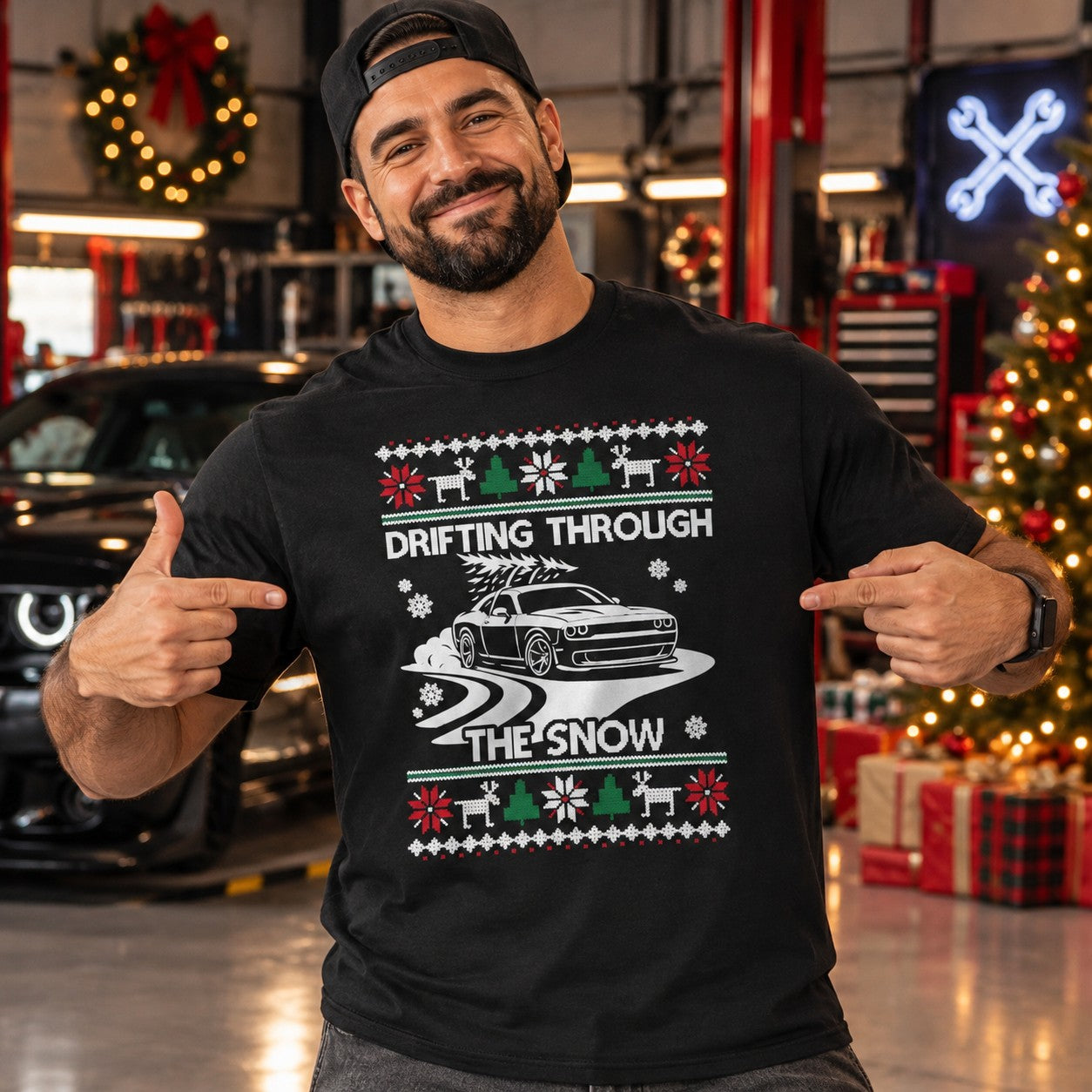 Man wearing the black Drifting Through the Snow muscle car t-shirt in a garage next to a Christmas tree