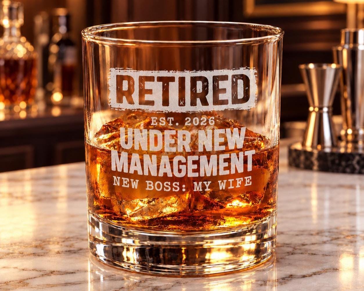 Retired Under New Management Whiskey Glass - glass on a marble bar with ice and whiskey