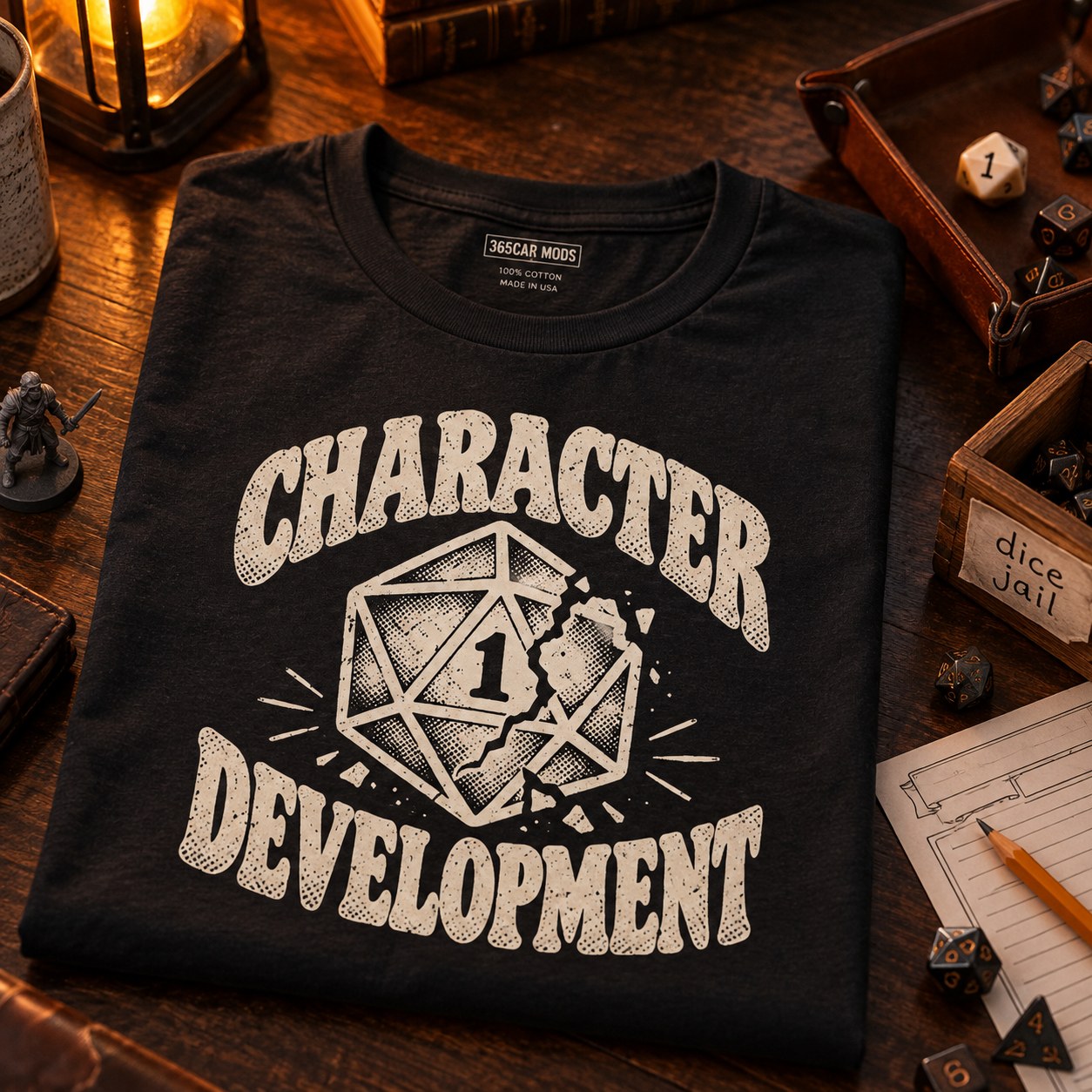 Character Development T-Shirt | Nat 1 D20 Tabletop RPG Tee in black, folded on a wooden game table with dice, miniatures and a character sheet.