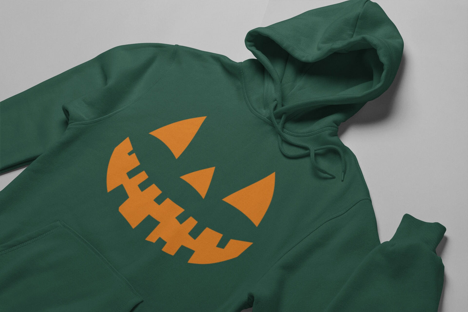 Forest Green hoodie with a large orange jack-o'-lantern face with pointed eyes, a triangle nose and a jagged toothy grin