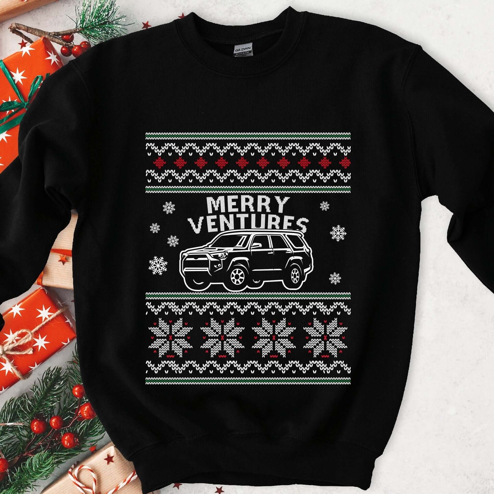 Dark sweatshirt with ugly sweater knit borders, MERRY VENTURES text and a white off-road SUV among snowflakes