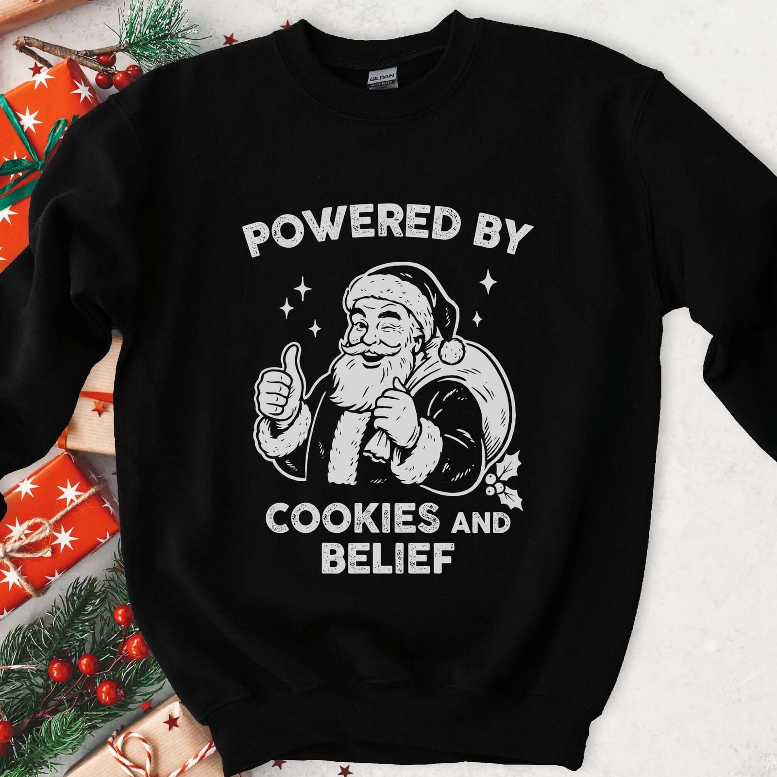 Dark sweatshirt with vintage gray art of a winking Santa giving a thumbs up, text Powered By Cookies and Belief