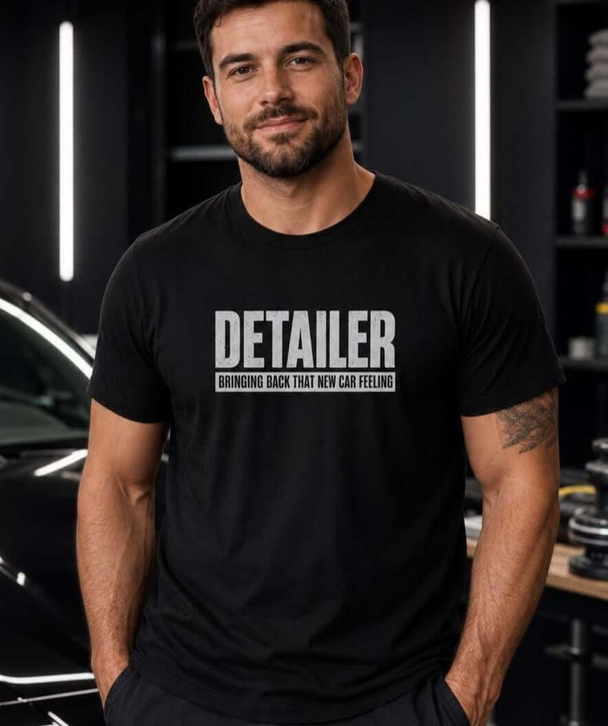 A black t-shirt with the word DETAILER in large distressed white letters and the text BRINGING BACK THAT NEW CAR FEELING.