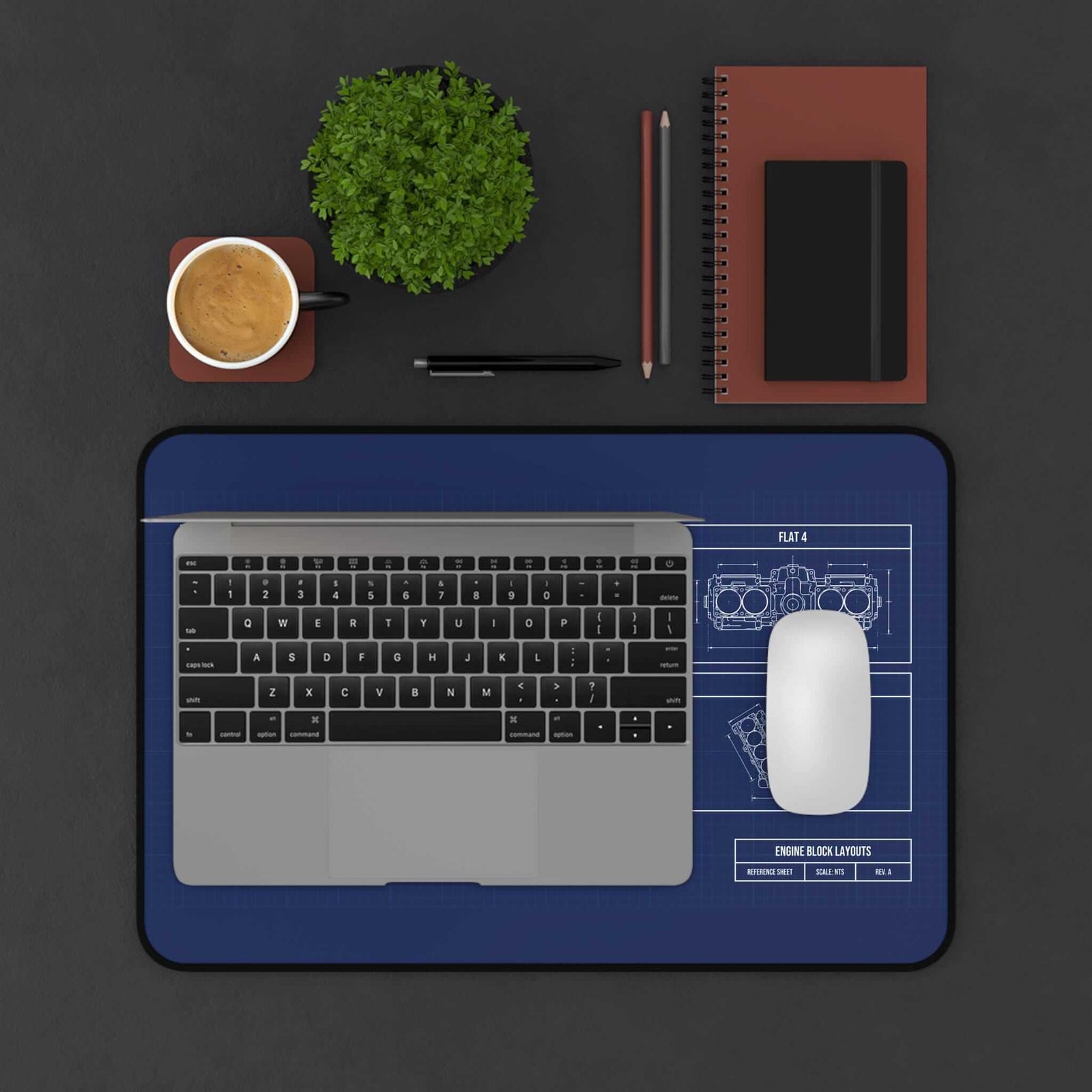 Engine block blueprint desk mat under a laptop and mouse, top view