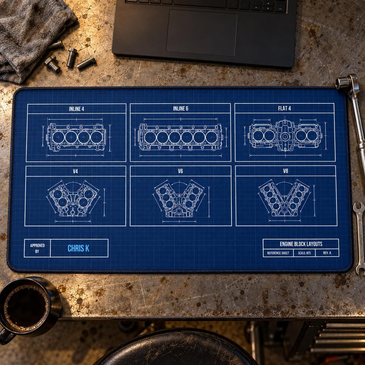 Engine block blueprint desk mat with six engine layouts and a personalized Approved By name on a garage workbench