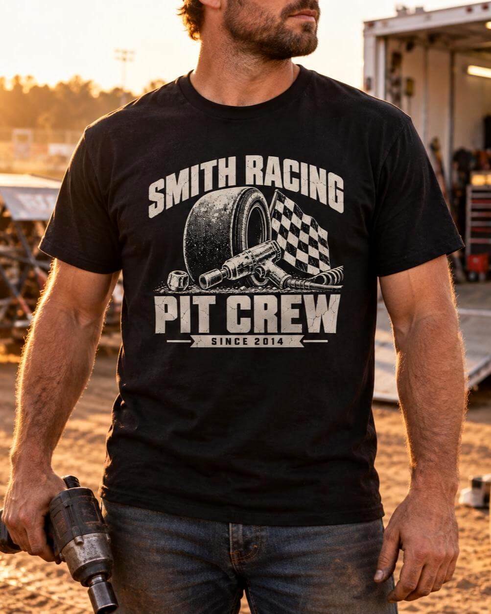 Man holding an impact wrench in a dirt track pit area, wearing the black personalized Pit Crew racing t-shirt