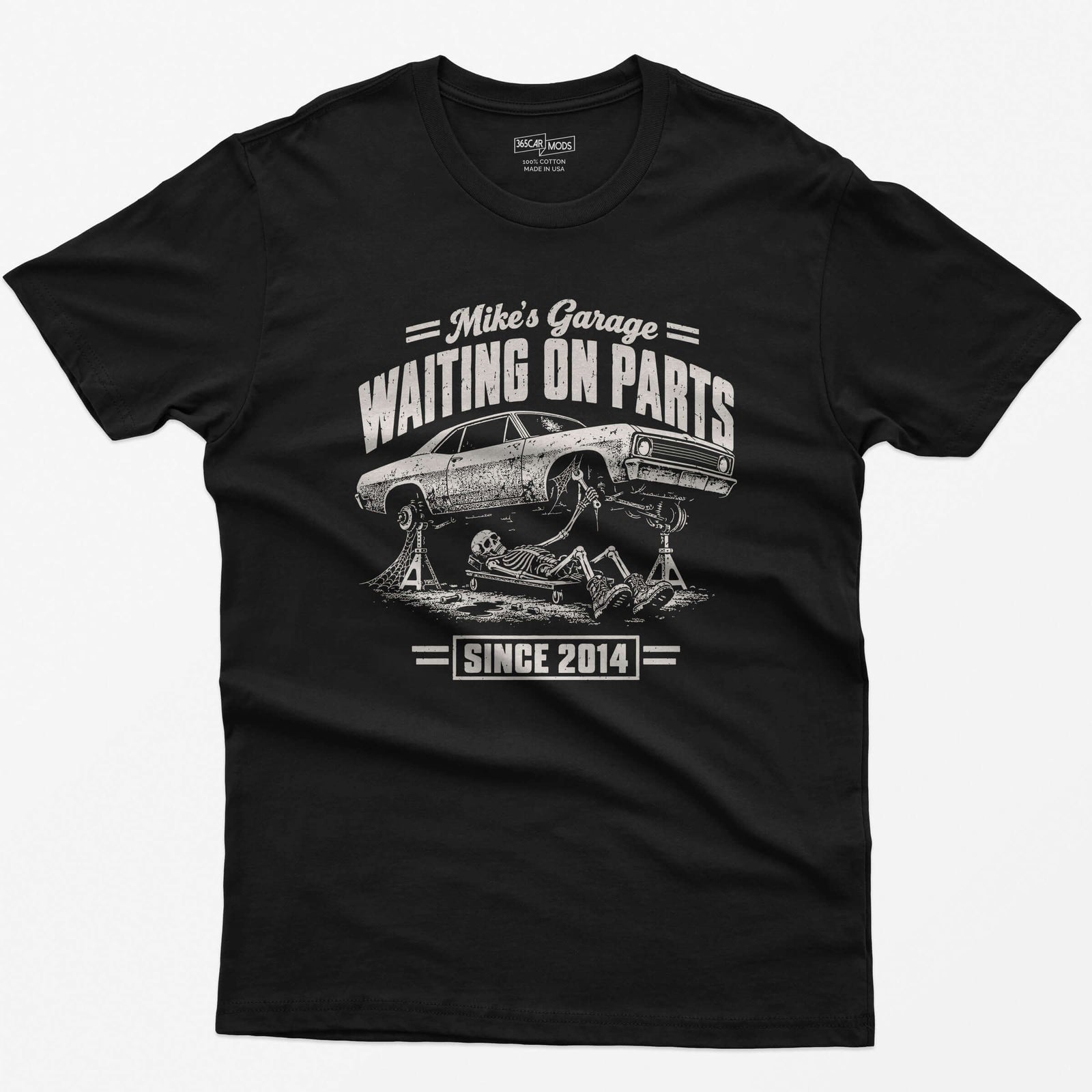 Black t-shirt with WAITING ON PARTS, a skeleton mechanic on a creeper under a project car on jack stands, Mike’s Garage on top and Since 2014 below