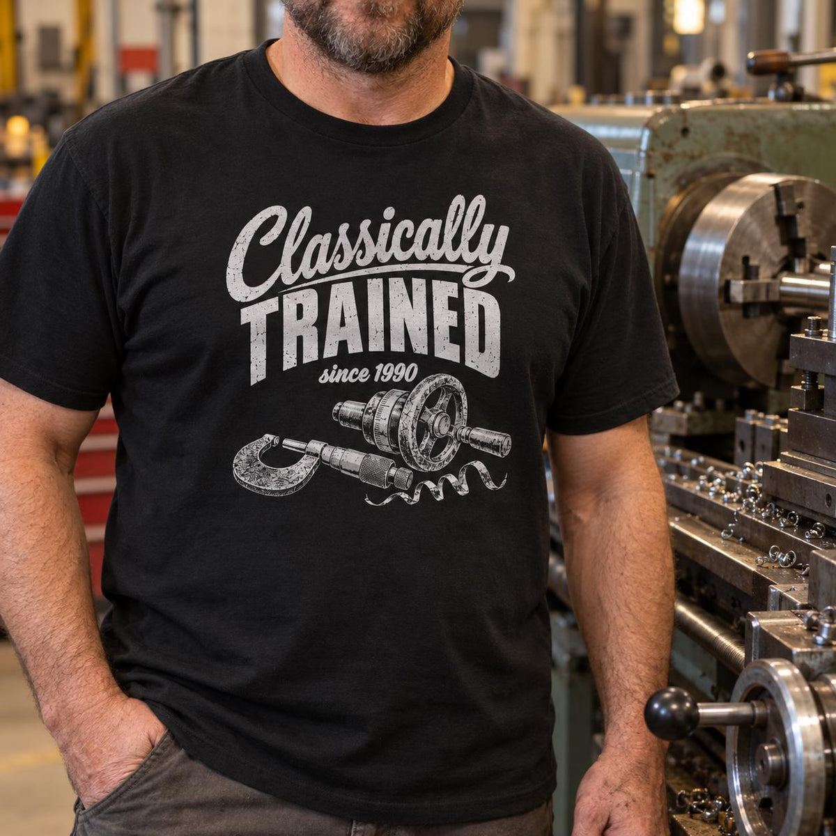 Man in a black Classically Trained machinist t-shirt standing in a machine shop next to a manual lathe