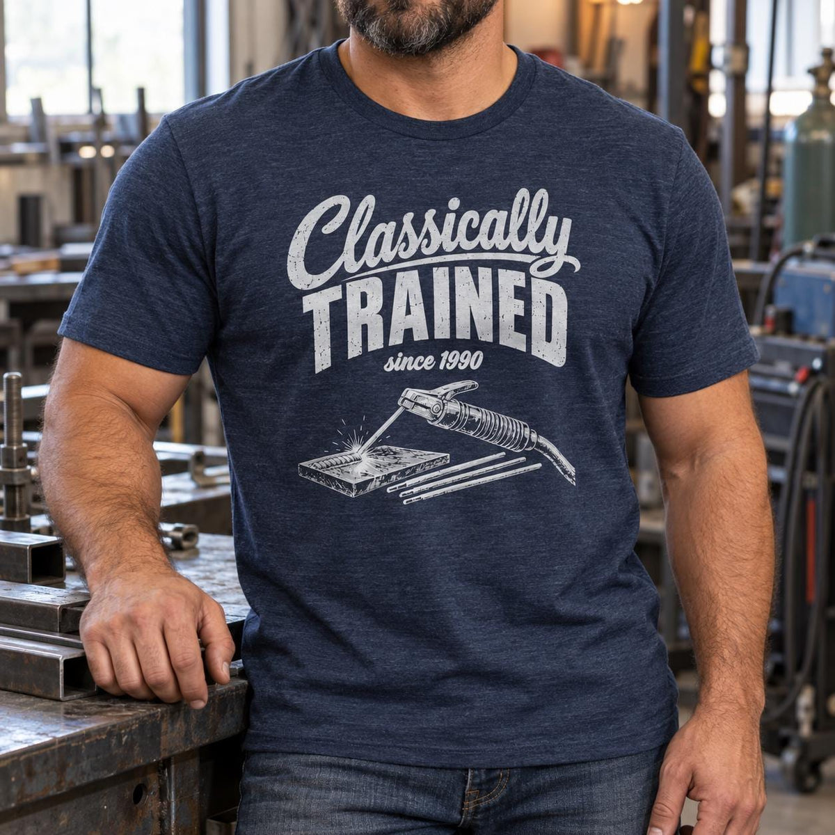 Welder in the Heather Navy Classically Trained t-shirt leaning on a shop bench