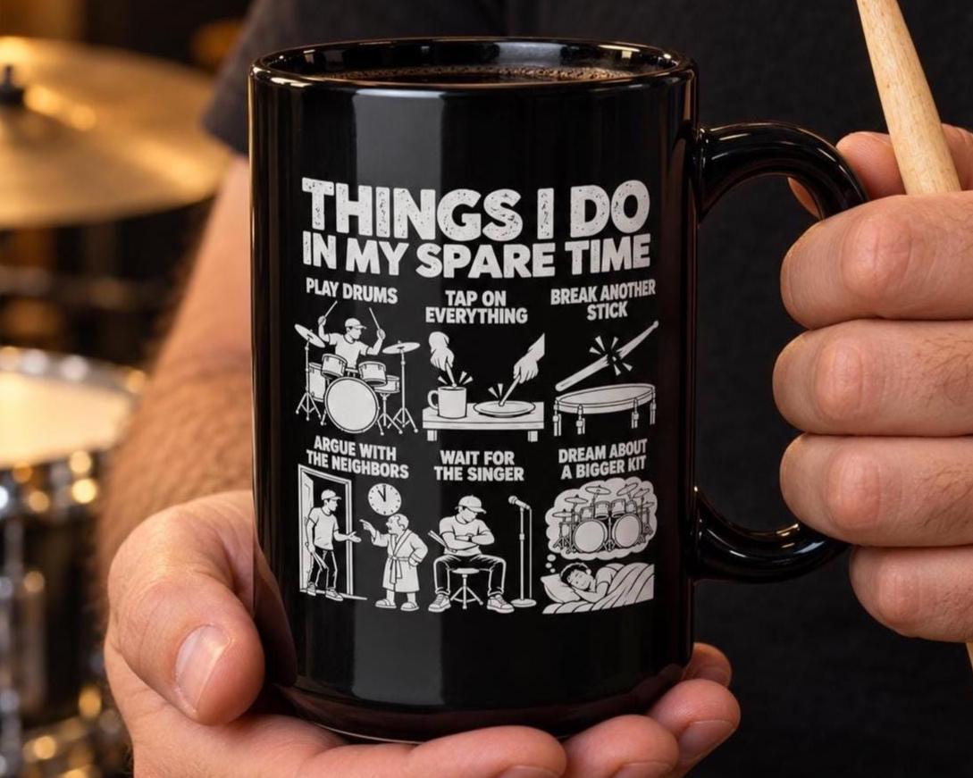 Drummer holding the black spare time mug next to his drum kit