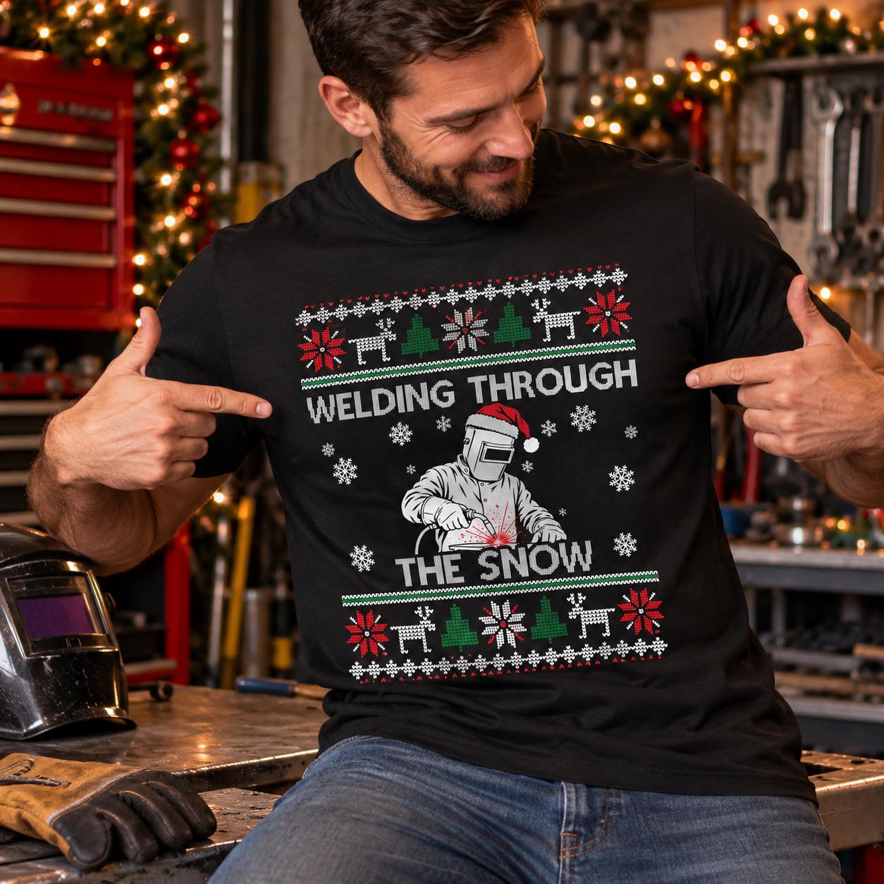 Welding Through the Snow Welder Christmas T-Shirt - welder wearing the black tee in a shop decorated for Christmas