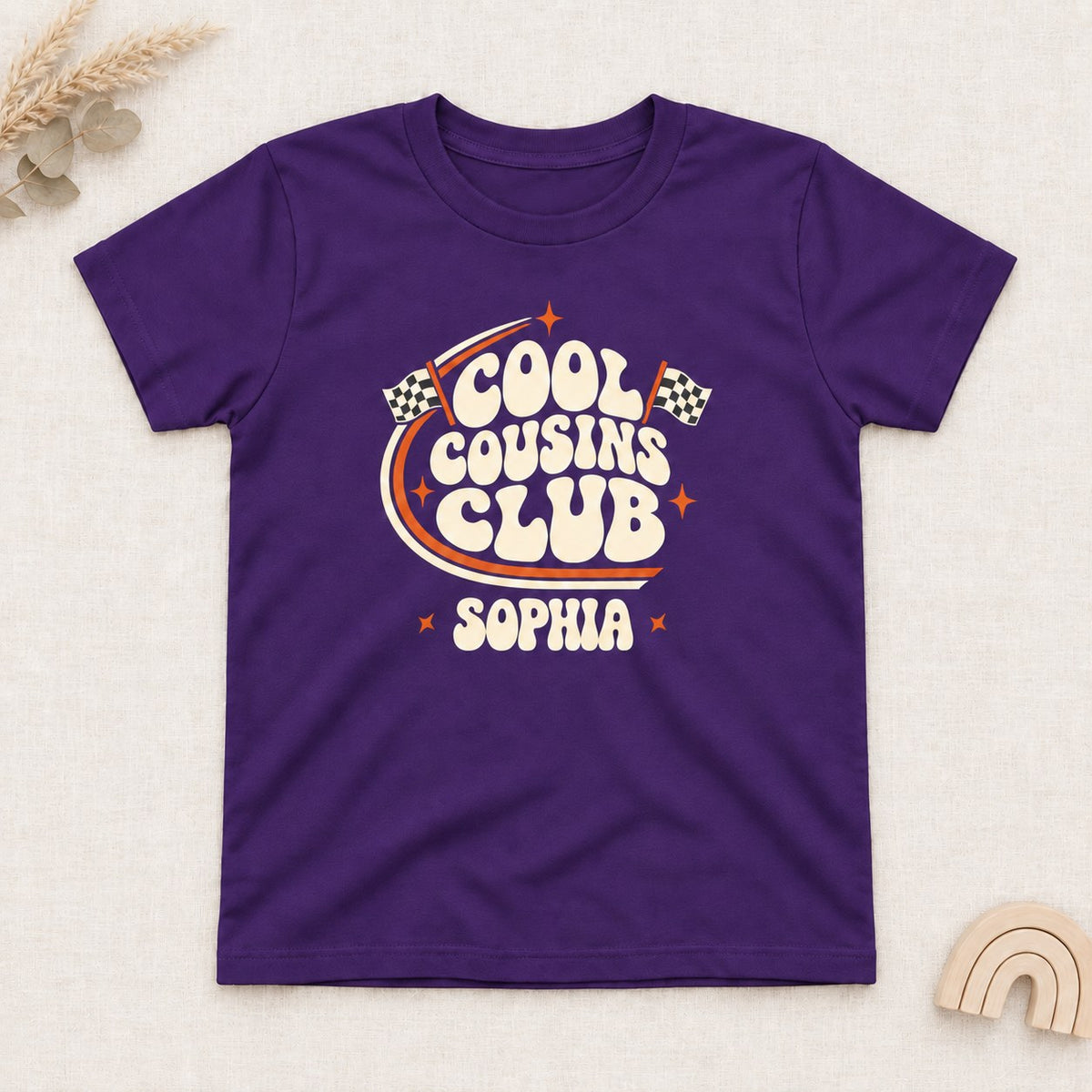 Purple t-shirt with a personalized Cool Cousins Club print with racing flags and a first name