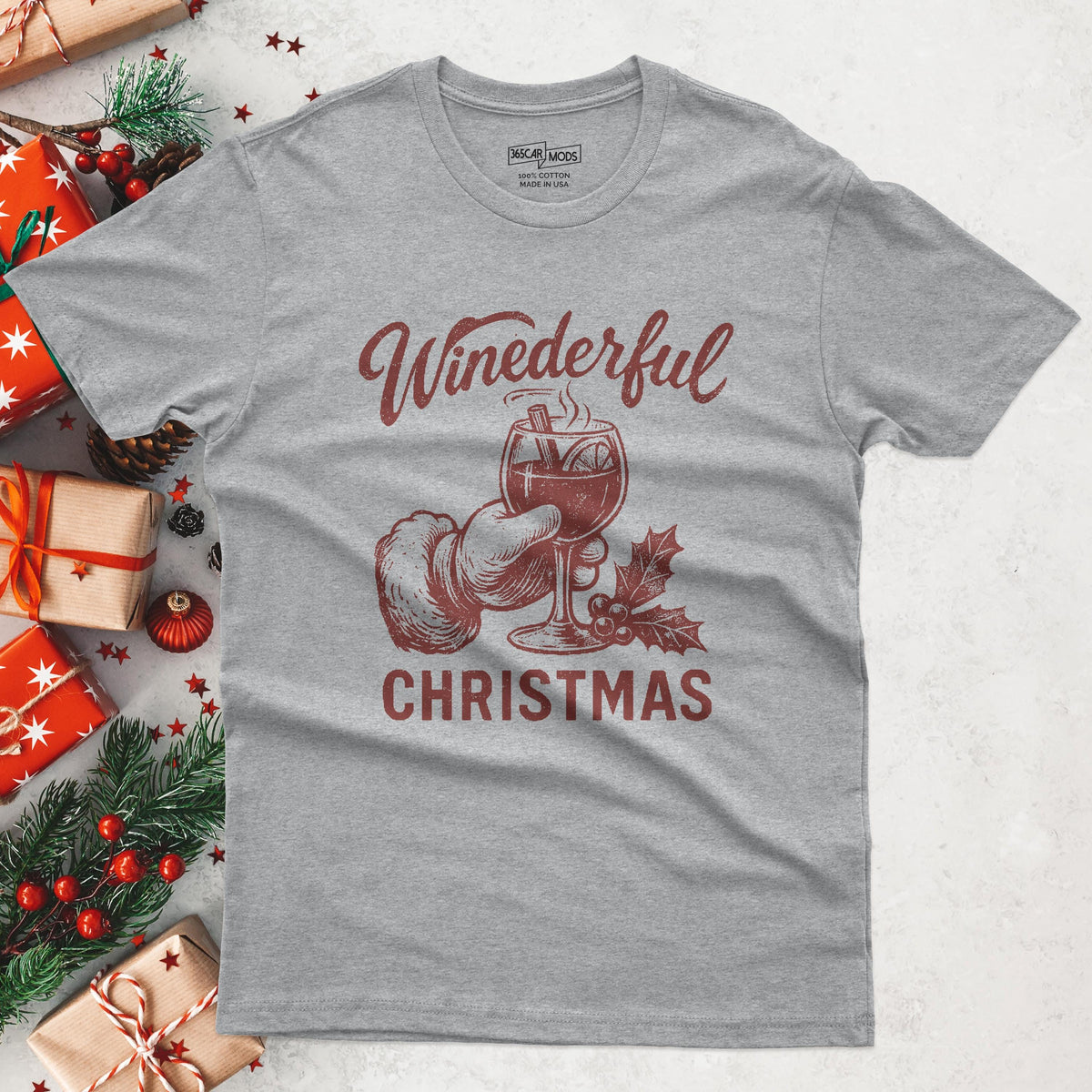 A heather gray t-shirt with a festive design. The graphic features a hand in a Santa glove holding a wine glass with the text "Winederful Christmas" in red. The shirt is made of a soft cotton blend.