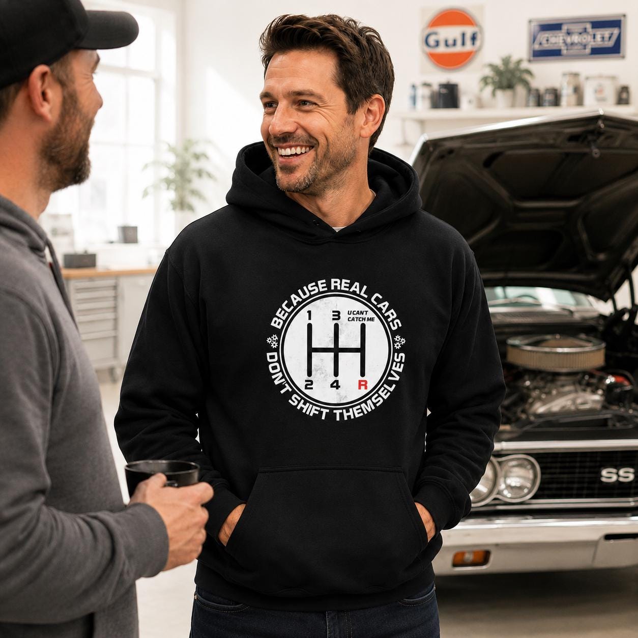 Black hoodie with BECAUSE REAL CARS DON'T SHIFT THEMSELVES around a white shift pattern circle with a red R