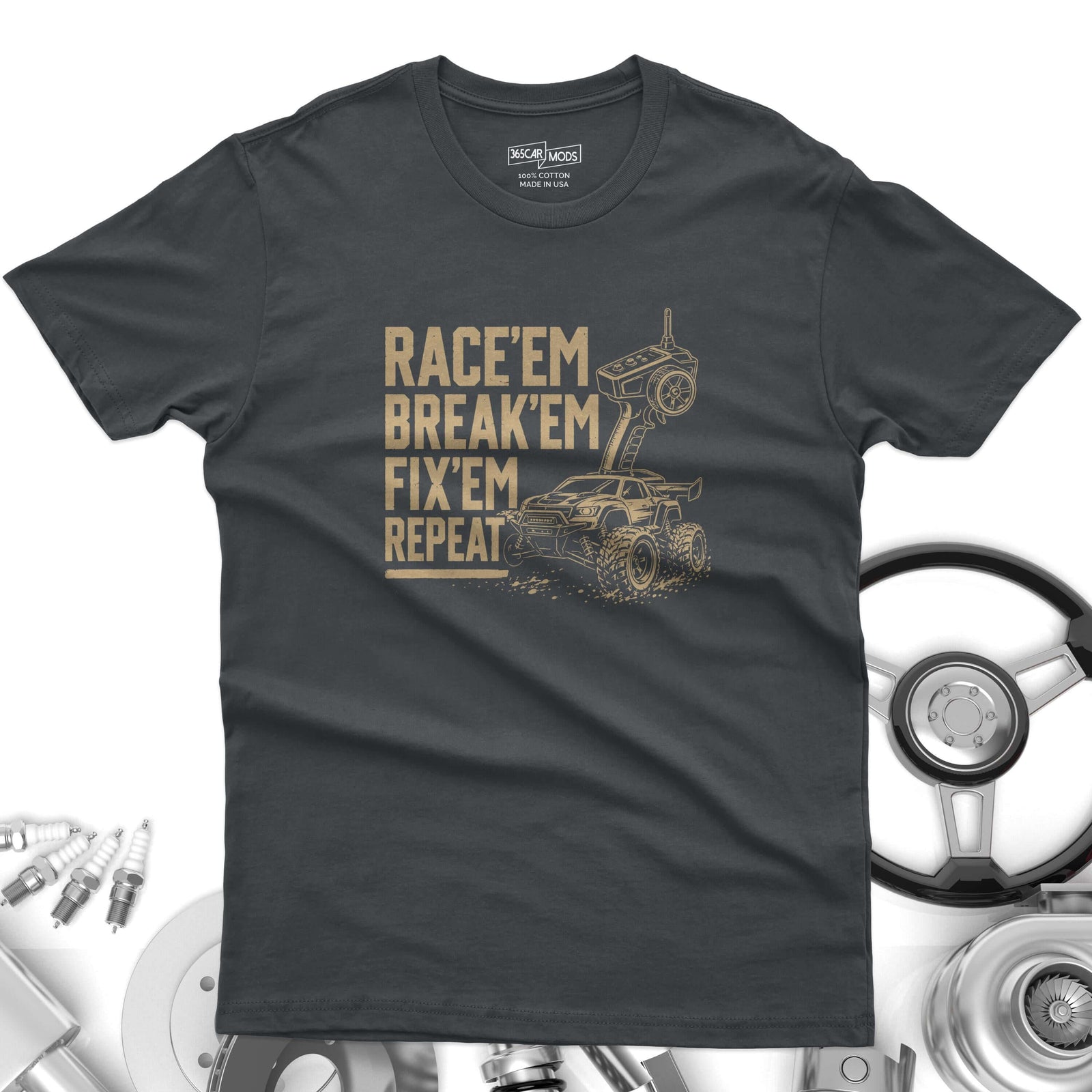 A charcoal gray short-sleeve t-shirt featuring a tan graphic of a remote-controlled truck and controller. The text reads: RACE'EM BREAK'EM FIX'EM REPEAT.