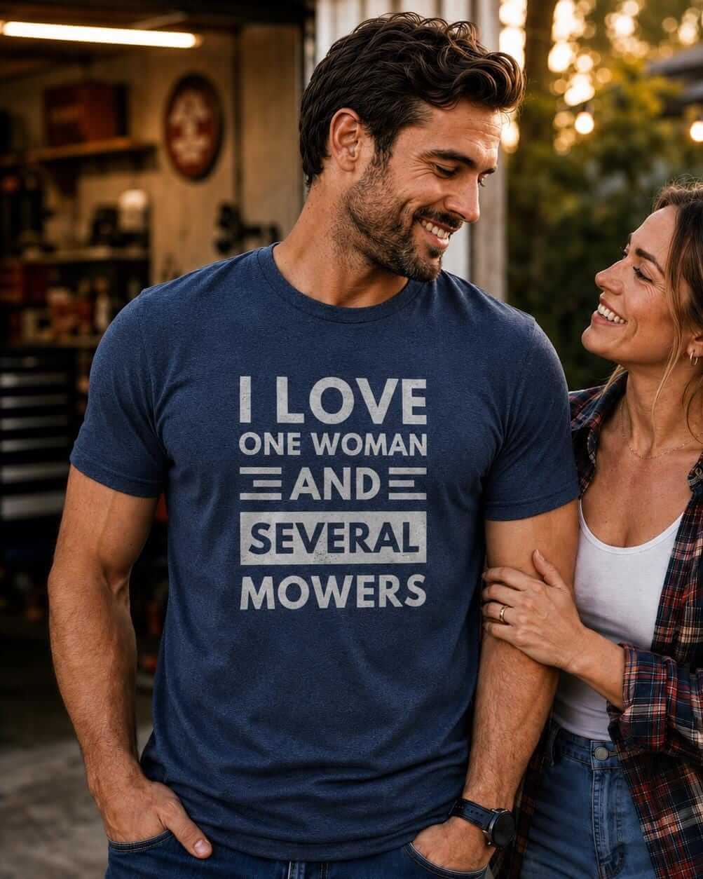 A navy blue short-sleeved crew neck t-shirt featuring the white distressed text I LOVE ONE WOMAN AND SEVERAL MOWERS printed on the front. The shirt has a standard fit and a soft, heathered texture throughout the fabric.