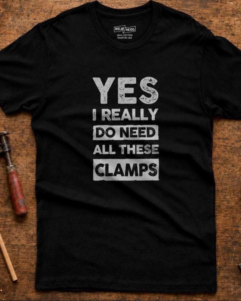 Black Yes I Really Do Need All These Clamps t-shirt hanging from mixed woodworking and welding clamps in a workshop