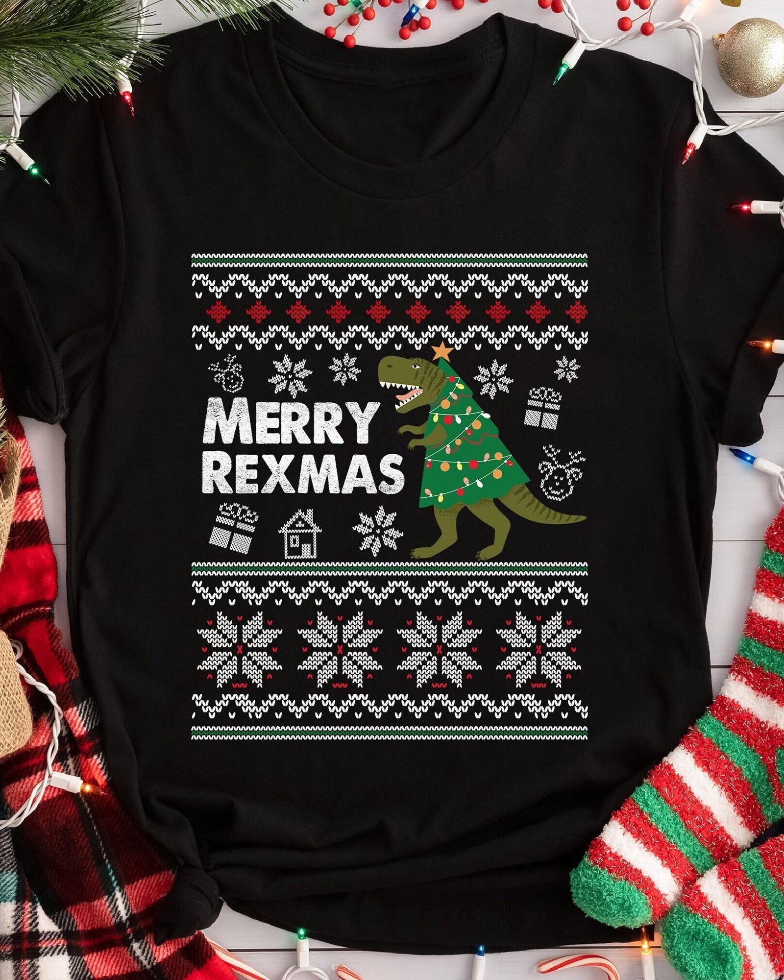A black short-sleeved t-shirt featuring a graphic print of a Tyrannosaurus Rex dressed as a Christmas tree with lights and a star.