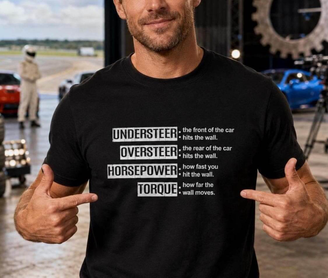 A black short-sleeved t-shirt featuring white text that defines automotive terms: UNDERSTEER: the front of the car hits the wall. OVERSTEER: the rear of the car hits the wall. HORSEPOWER: how fast you hit the wall.