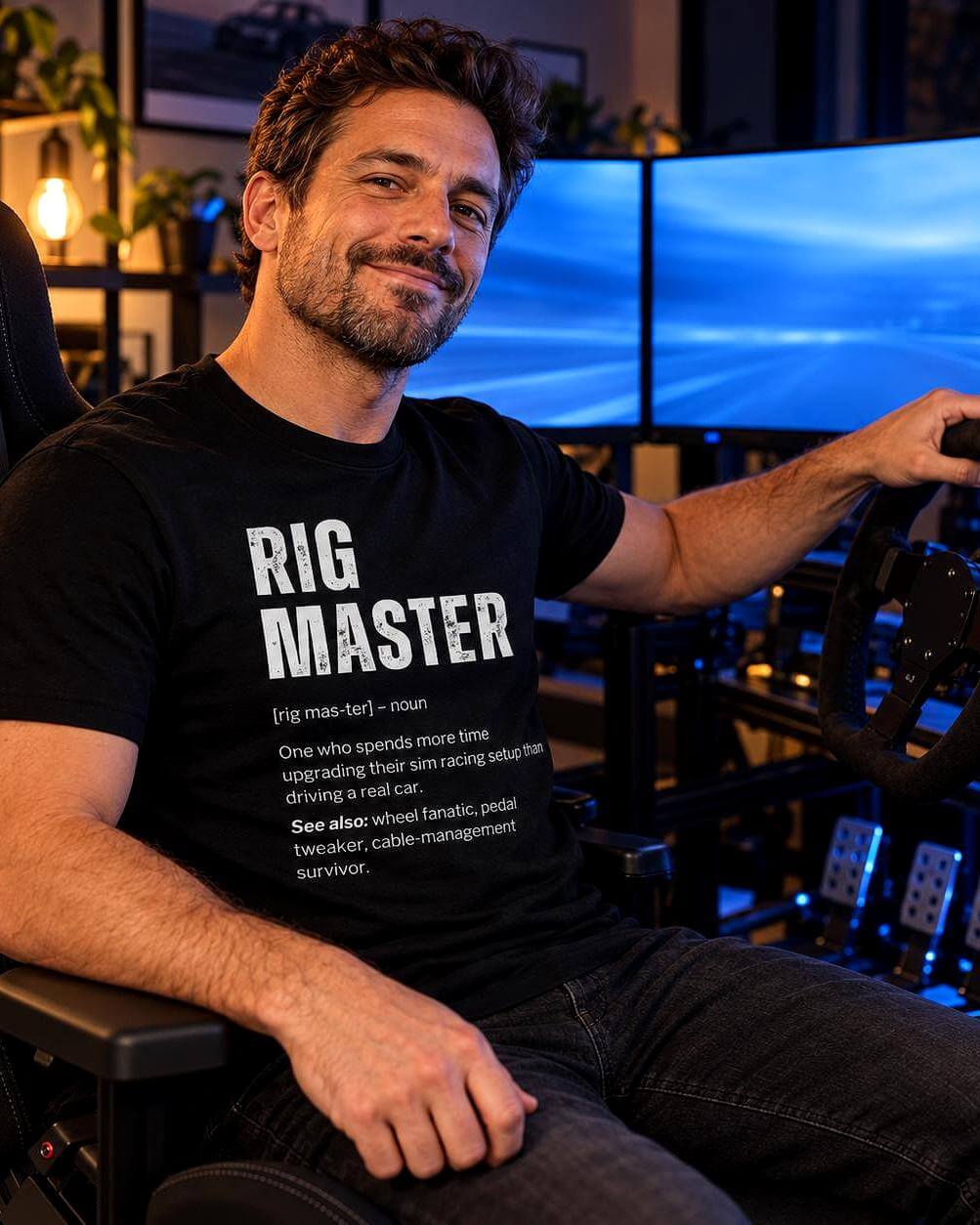 Man wearing a black Rig Master sim racing t-shirt while sitting in a full racing simulator setup with triple monitors, steering wheel, pedals and shifter.