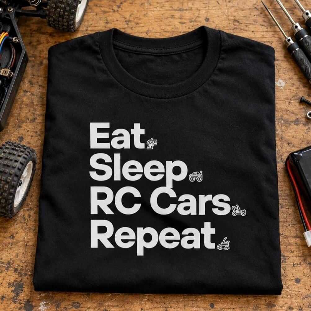 Folded black RC car shirt on a workbench next to an RC buggy, hex drivers and a battery pack
