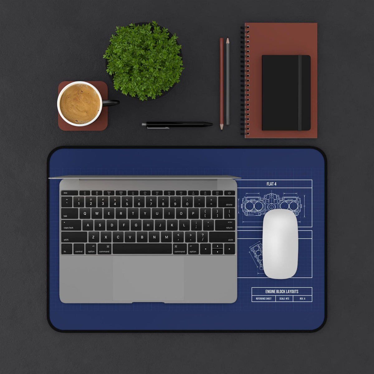Engine block blueprint desk mat under a laptop and mouse, top view