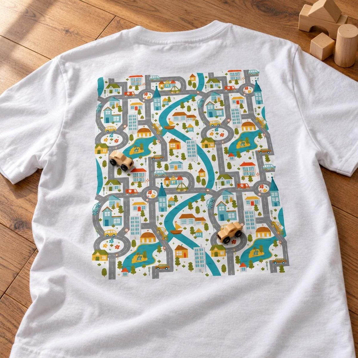 Close-up of the road play mat print on the back of a white t-shirt with two wooden toy cars