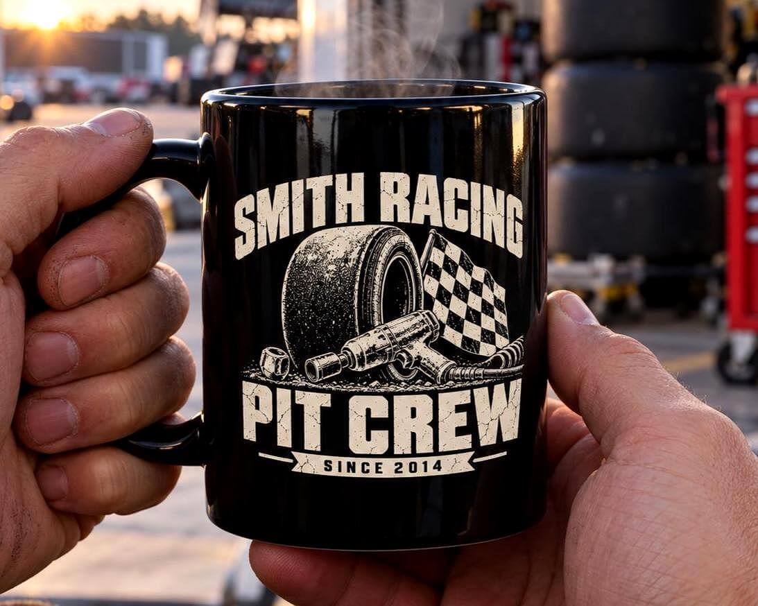 Hands holding the black personalized Pit Crew racing mug in front of a race trailer at dawn