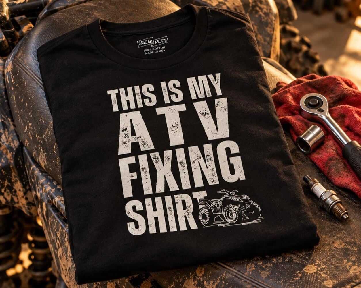 Folded black ATV fixing shirt on the seat of a muddy quad next to a spark plug and a wrench