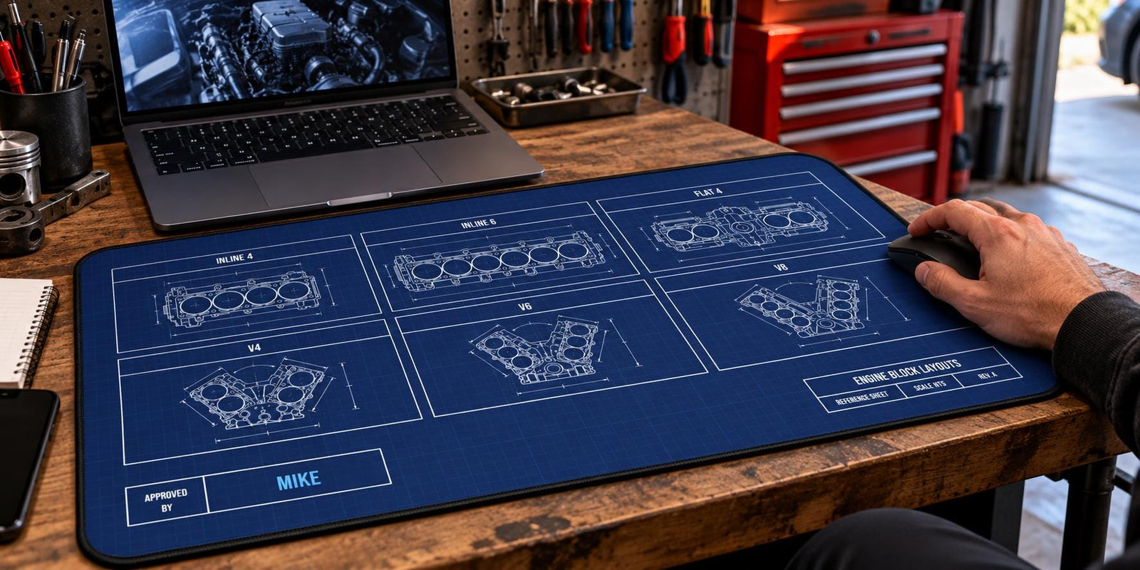 Extended engine block blueprint desk mat in a home garage with laptop