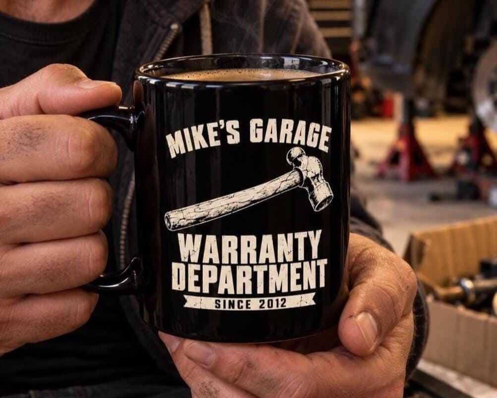 Hands holding the personalized Warranty Department coffee mug in a garage