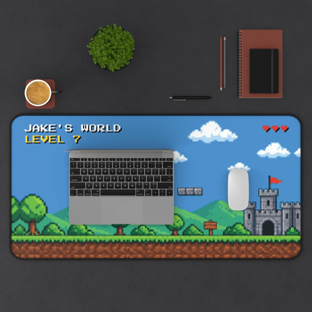 Pixel art desk mat under a laptop and white mouse on a dark desk