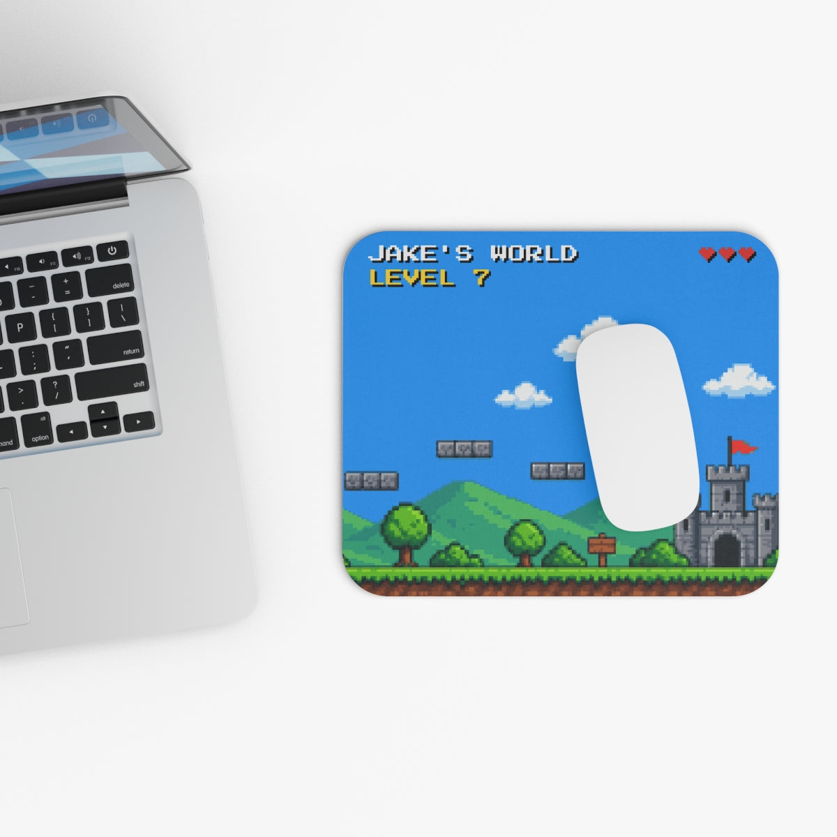 Personalized pixel art mouse pad next to a laptop