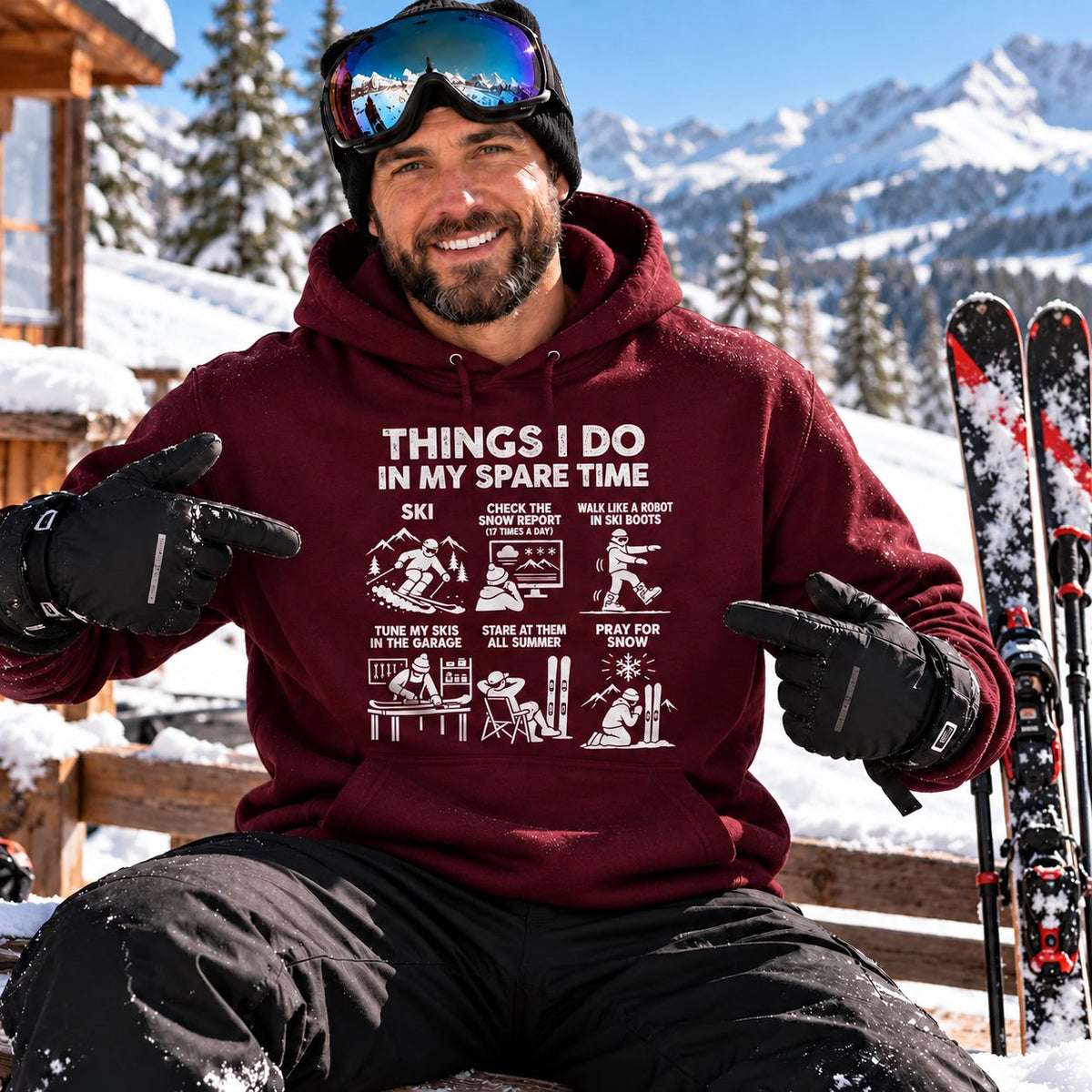 Skier in the maroon ski hoodie on the deck of a ski lodge, snowy peaks behind