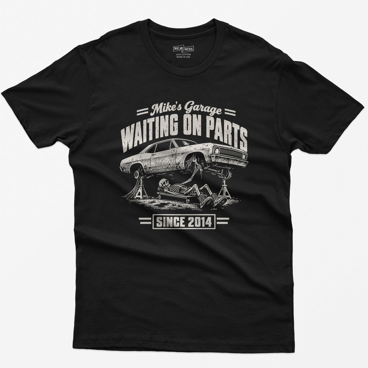 Black t-shirt with WAITING ON PARTS, a skeleton mechanic on a creeper under a project car on jack stands, Mike’s Garage on top and Since 2014 below